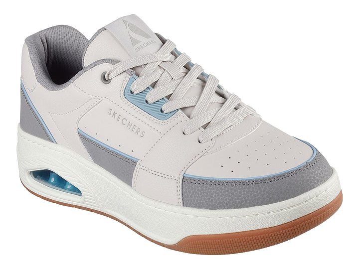 Tenis Skechers One Court color beige y gris con suela marrón y cámara de aire en el talón.