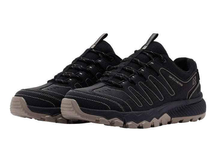 Zapato deportivo Skechers color negro con suela rugosa en tono beige.