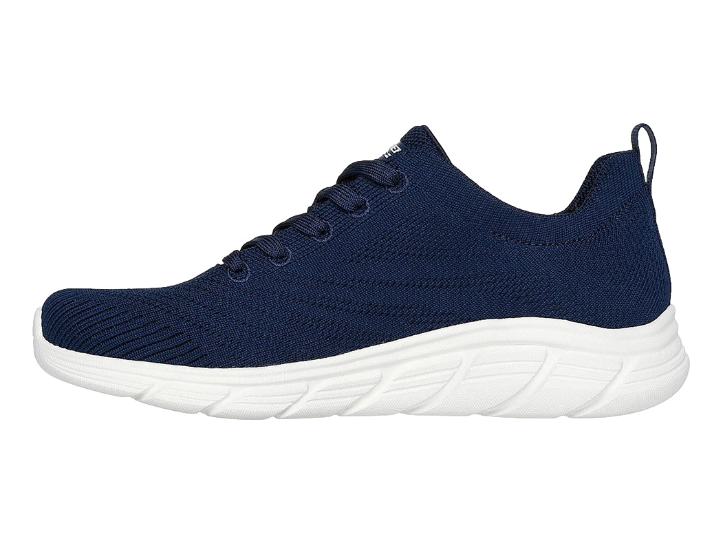 Tenis Skechers azul marino con suela blanca y cordones, diseño deportivo y tejido transpirable.