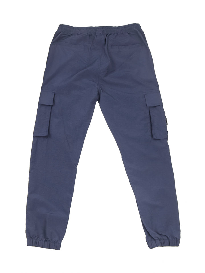 Hombre vistiendo pantalón jogger cargo color azul marino con camiseta blanca y tenis beige.