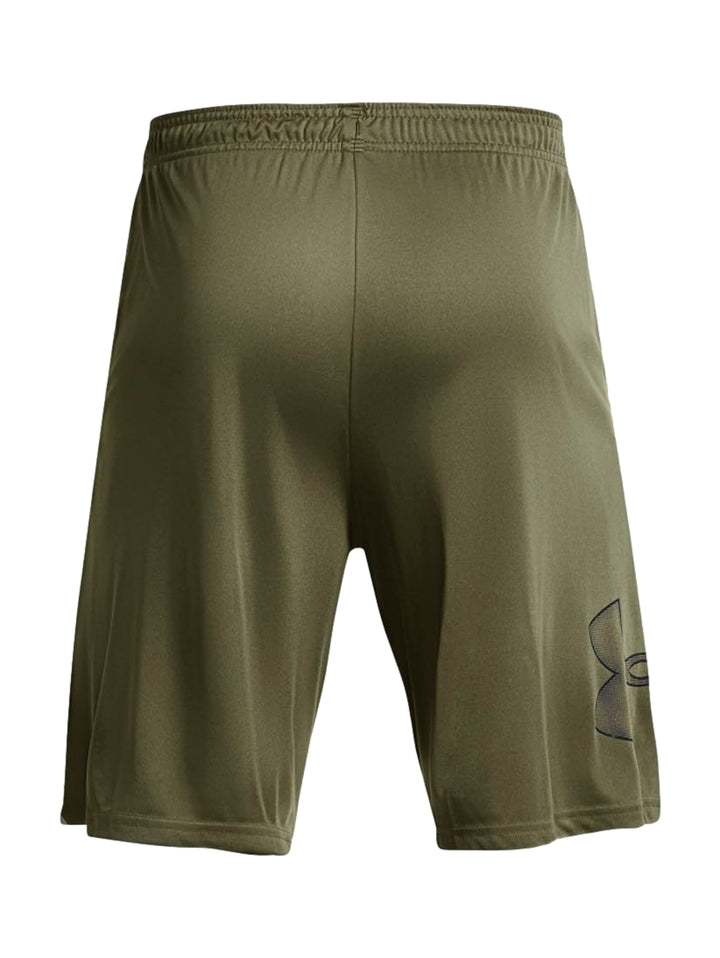 Hombre vistiendo shorts deportivos Under Armour color verde oliva con camiseta negra y tenis negros.