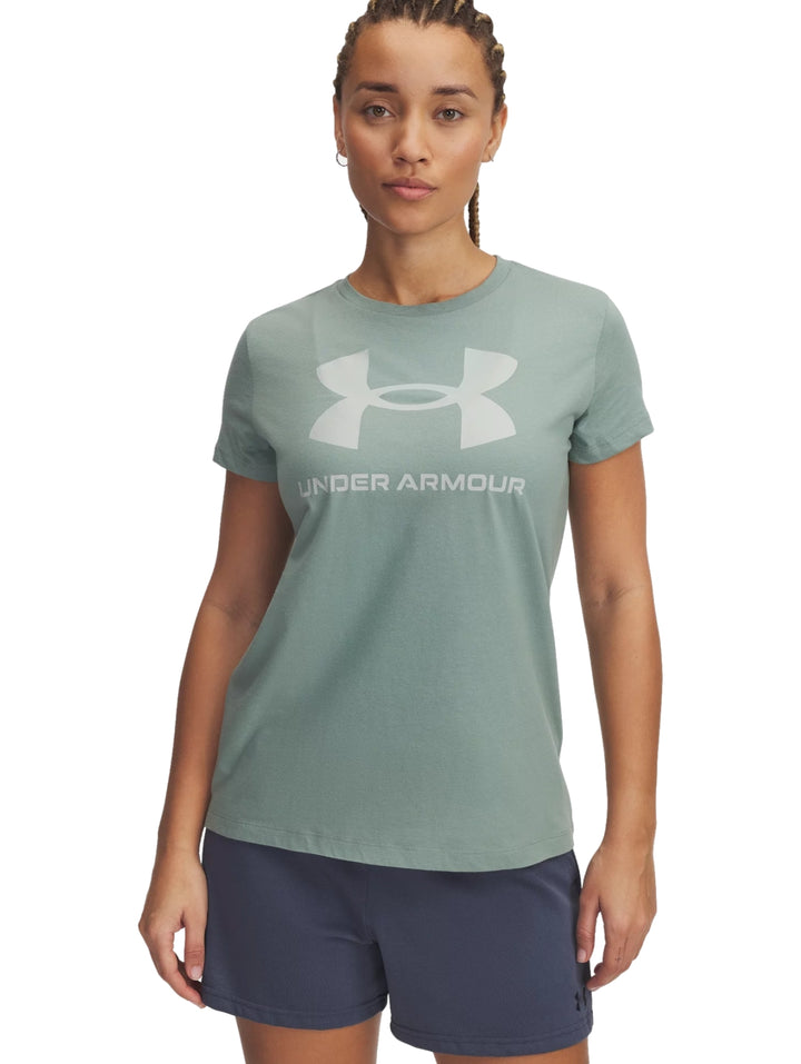 Mujer vistiendo una camiseta deportiva verde claro con logotipo de Under Armour en el centro.
