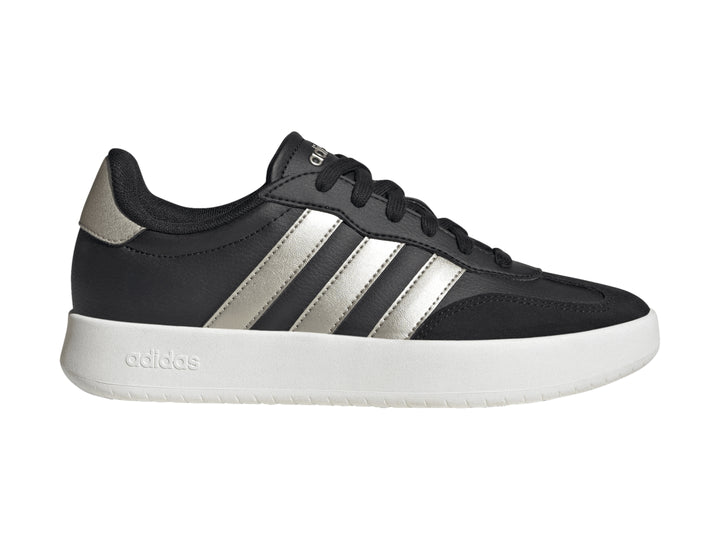 Tenis Adidas color negro con tres franjas doradas y suela blanca.