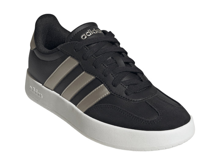 Tenis Adidas color negro con tres franjas doradas y suela blanca.