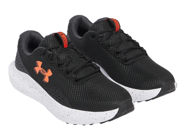 Tenis deportivos Under Armour color negro con suela blanca y logotipo naranja en el costado.