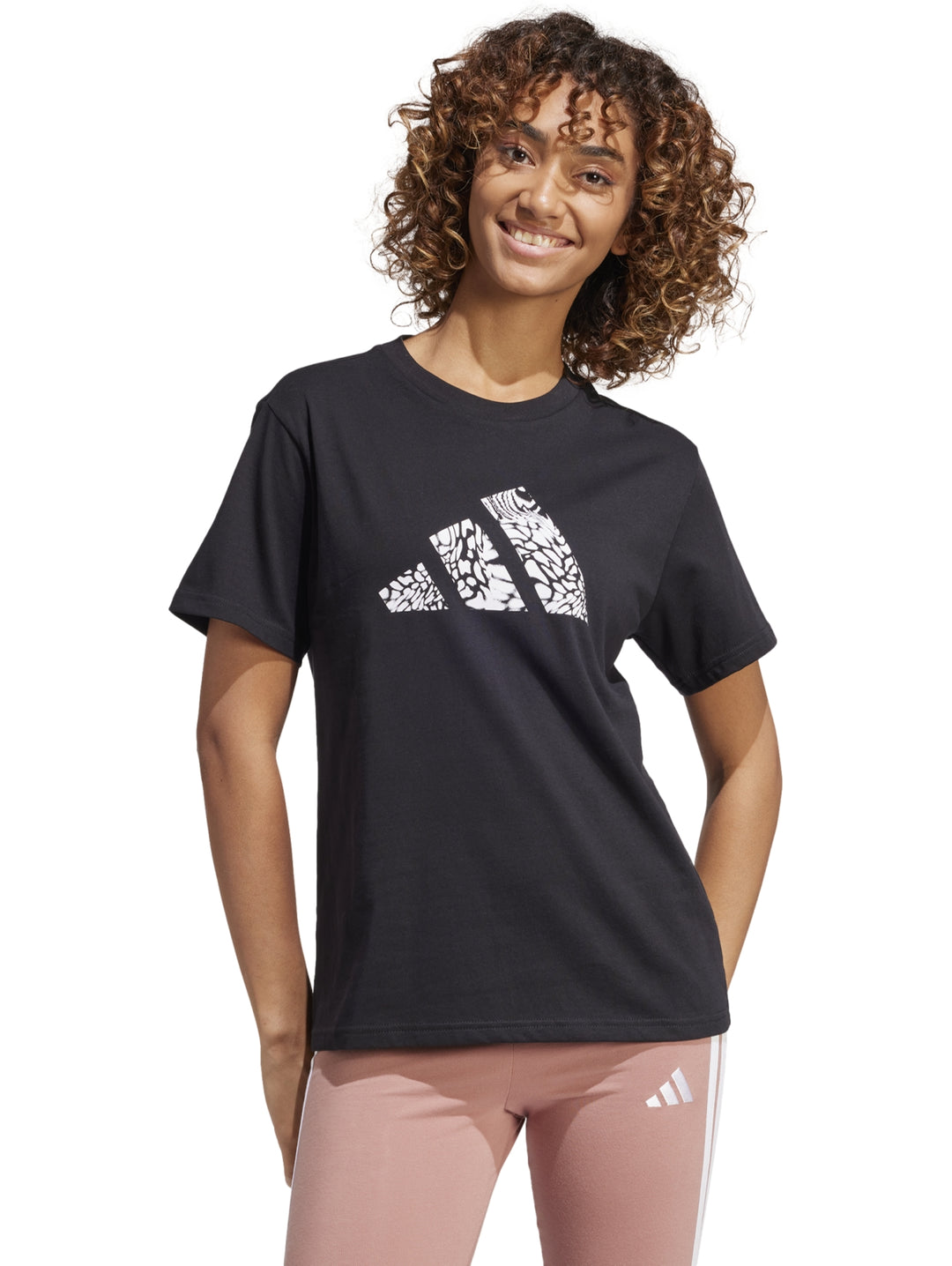 Mujer vistiendo camiseta deportiva negra de manga corta con logotipo gráfico de Adidas en el pecho.