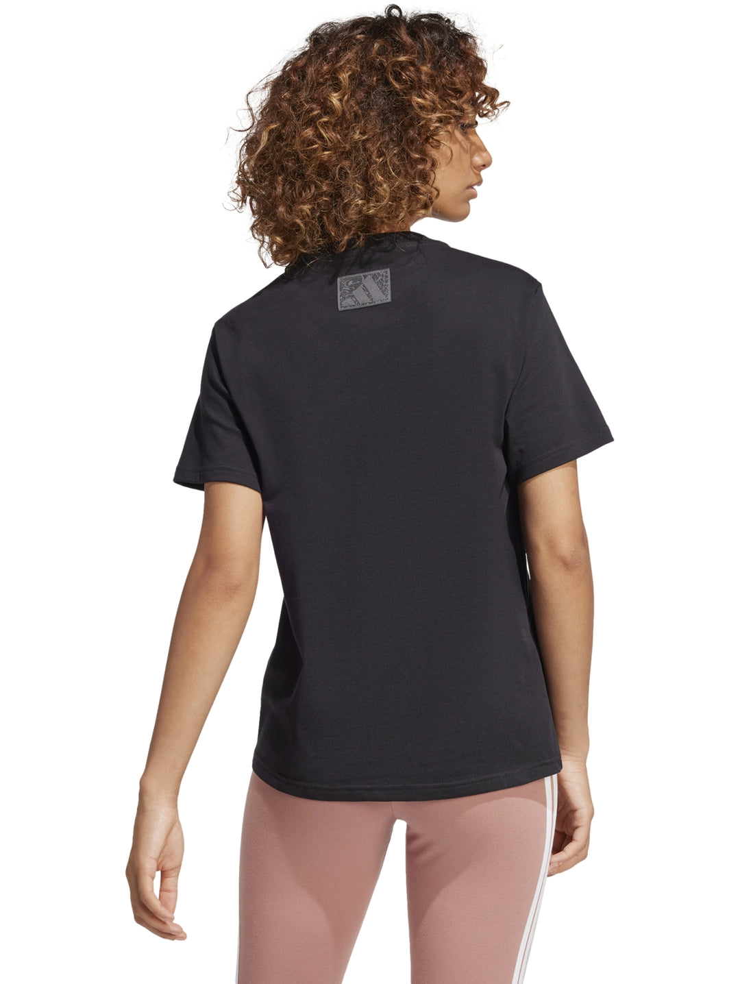 Mujer vistiendo camiseta deportiva negra de manga corta con logotipo gráfico de Adidas en el pecho.