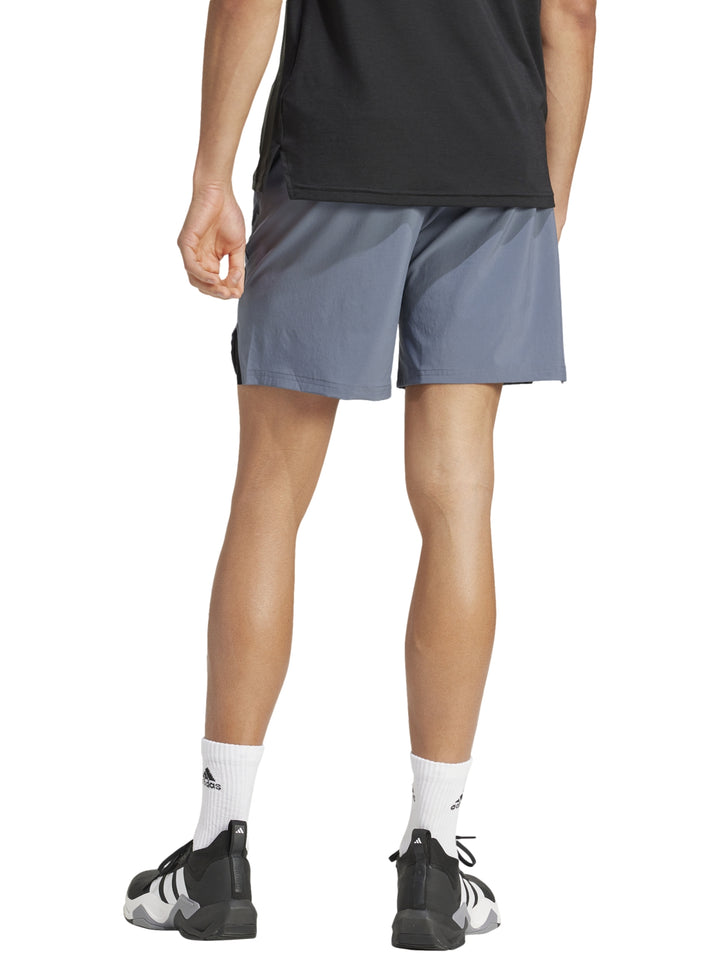Hombre vistiendo shorts deportivos Adidas color gris onix diseñados para entrenamiento.