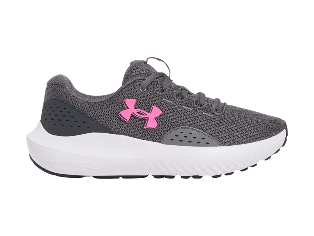 Tenis deportivos Under Armour color gris con suela blanca y logotipo rosa.