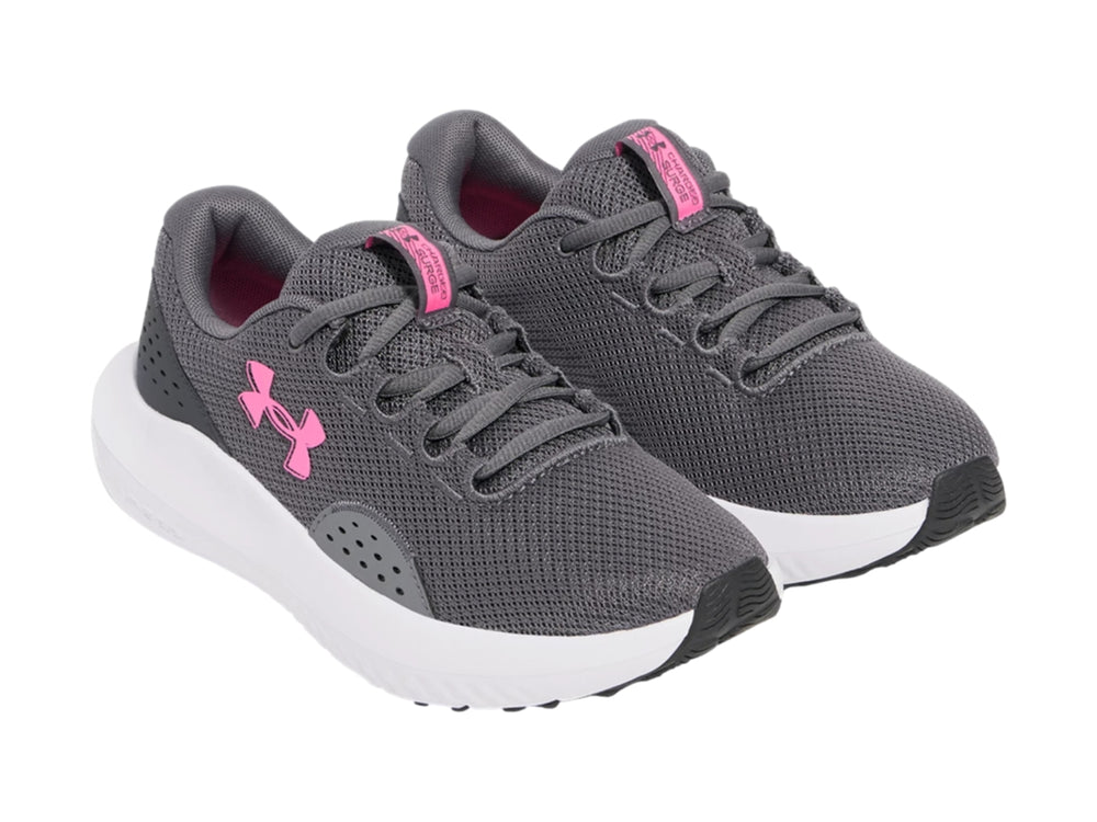 Tenis deportivos Under Armour color gris con suela blanca y logotipo rosa.