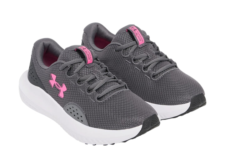 Tenis deportivos Under Armour color gris con suela blanca y logotipo rosa.