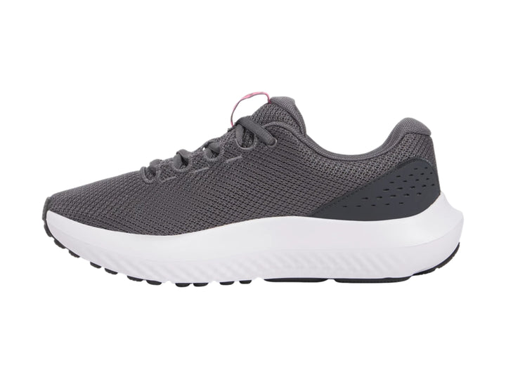 Tenis deportivos Under Armour color gris con suela blanca y logotipo rosa.