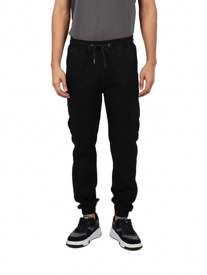 Hombre vistiendo pantalones jogger color negro con bolsillos laterales tipo cargo y puños ajustados.