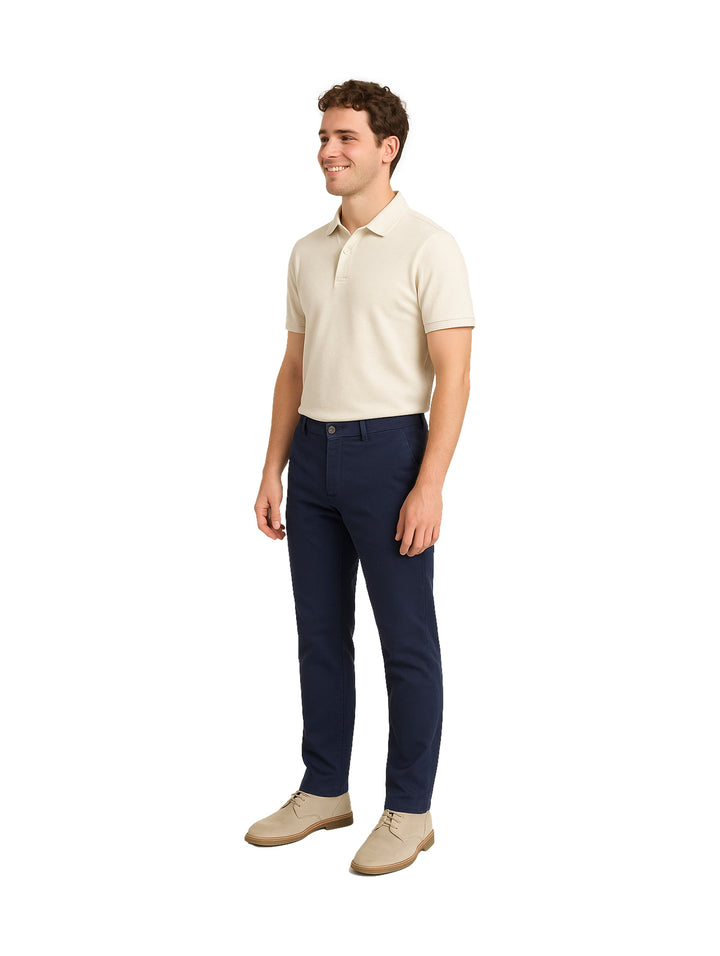 Hombre vistiendo un pantalón color marino de corte ajustado y una playera polo beige.