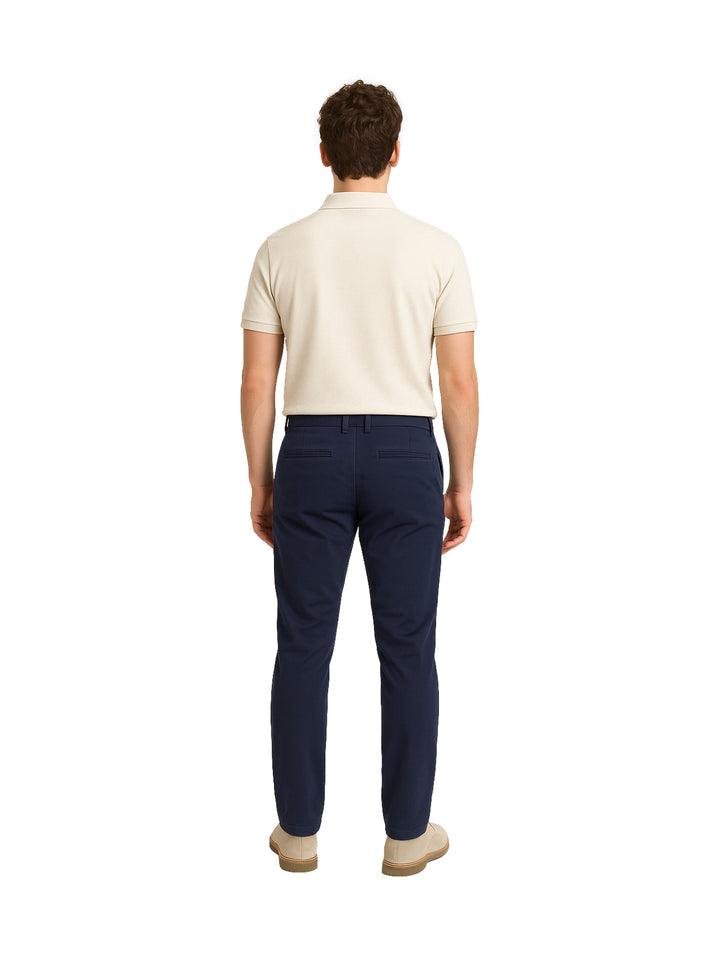 Hombre vistiendo un pantalón color marino de corte ajustado y una playera polo beige.