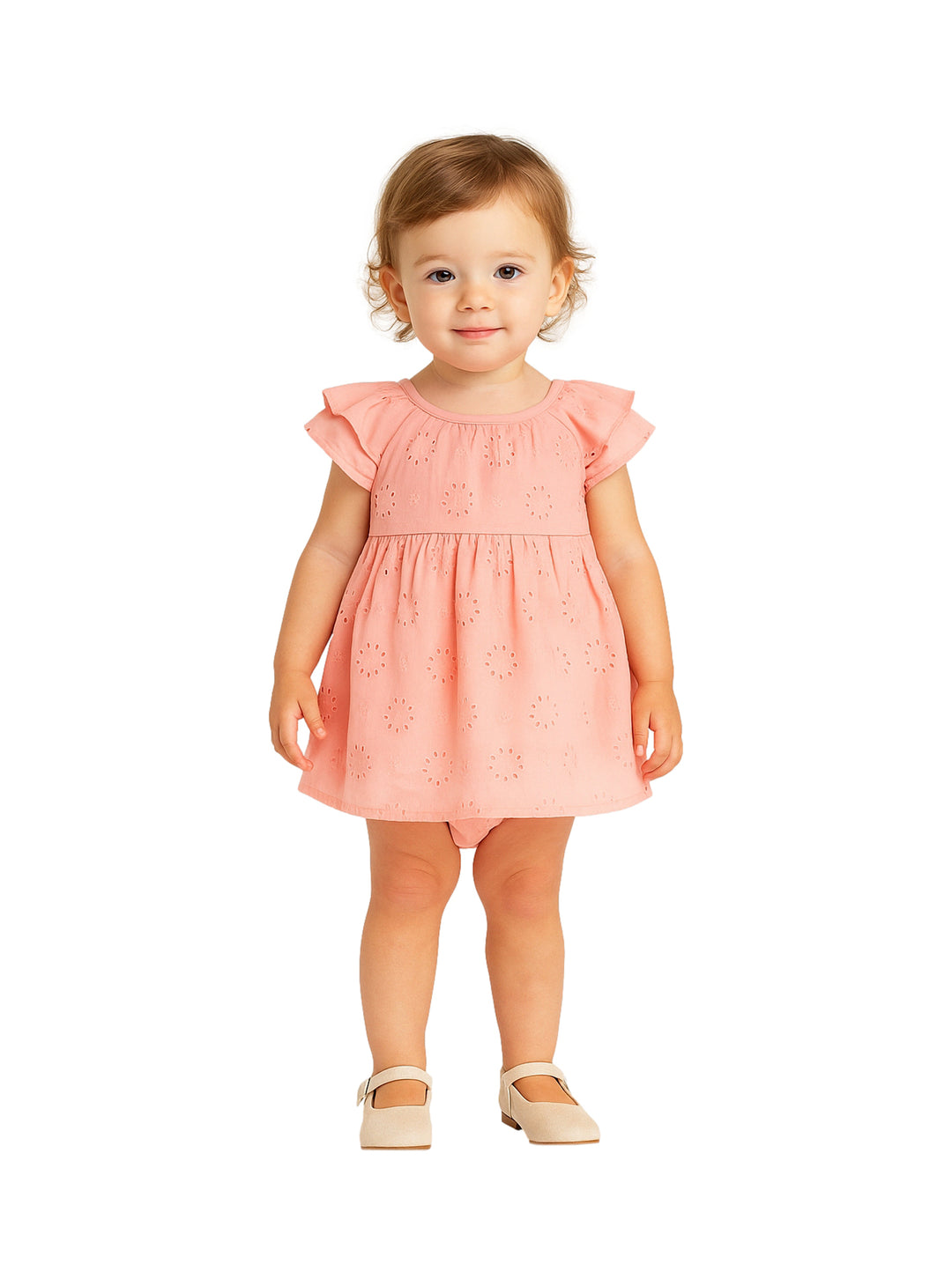 Niña pequeña vistiendo un vestido color durazno con detalles perforados y zapatos beige.
