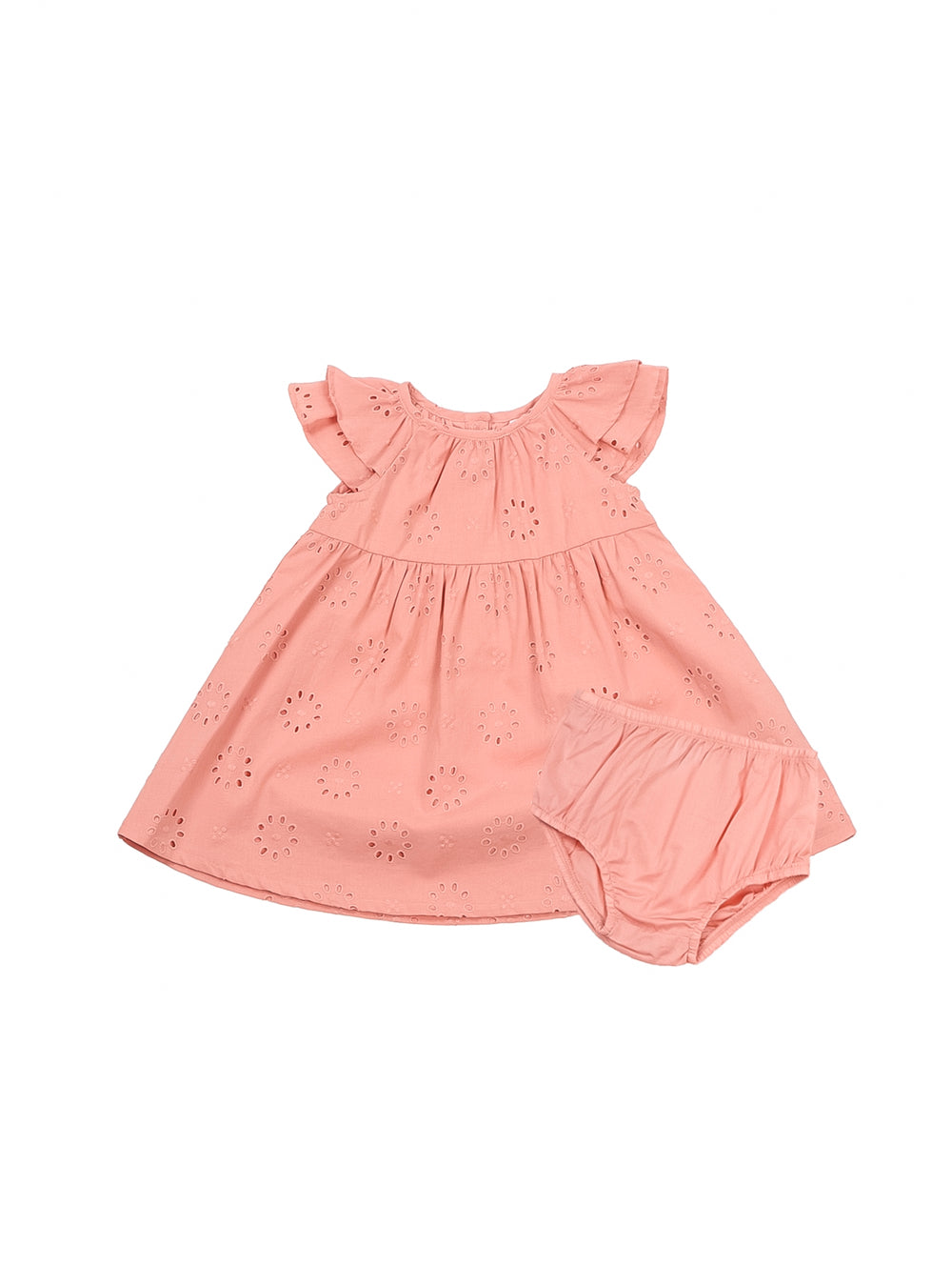 Niña pequeña vistiendo un vestido color durazno con detalles perforados y zapatos beige.