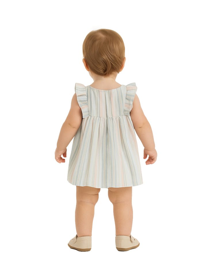 Niña pequeña vistiendo un vestido corto de rayas en tonos pastel con botones frontales y volantes en los hombros.