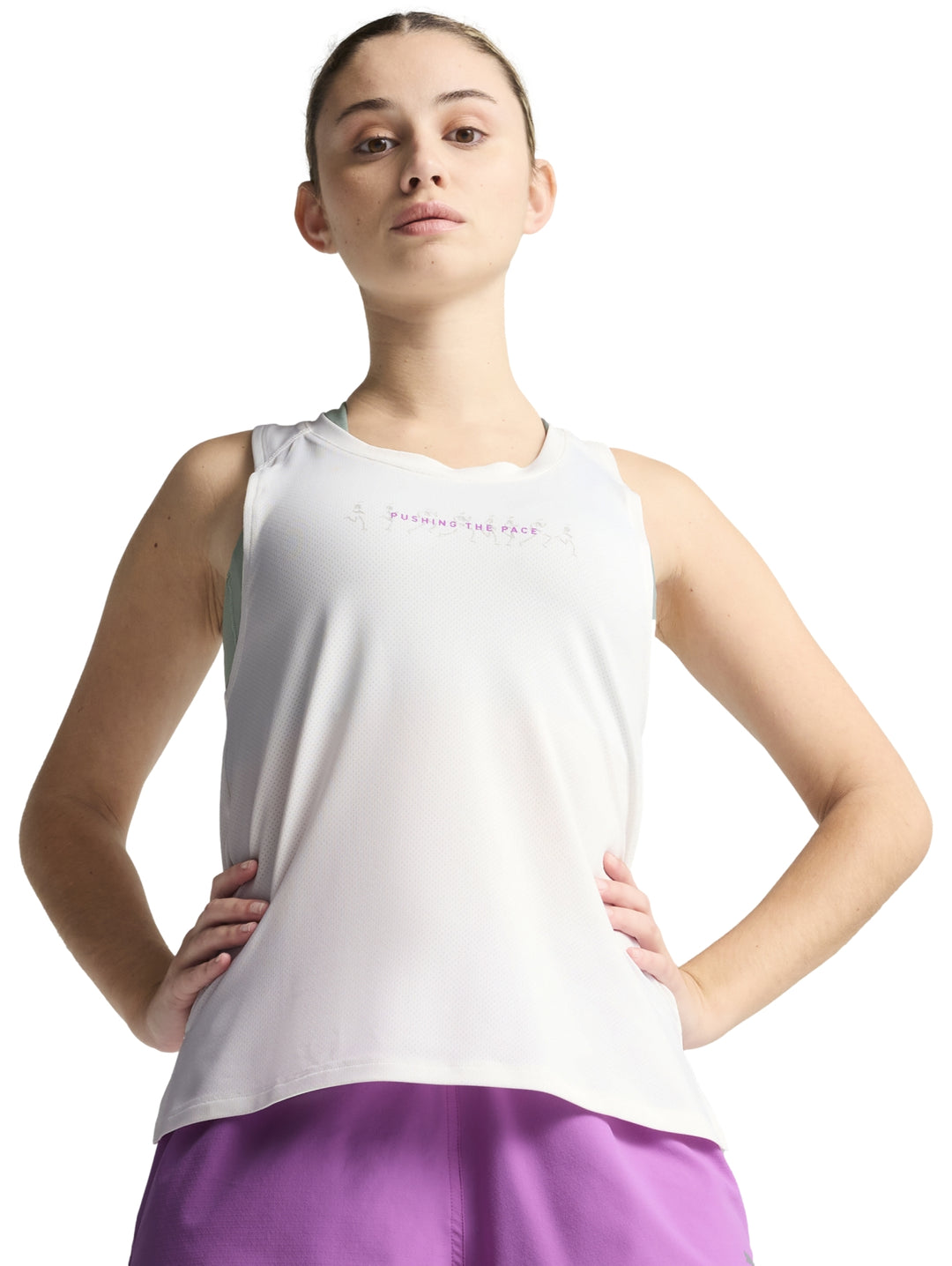 Mujer vistiendo una camiseta deportiva blanca sin mangas de la marca PUMA con gráfico frontal.