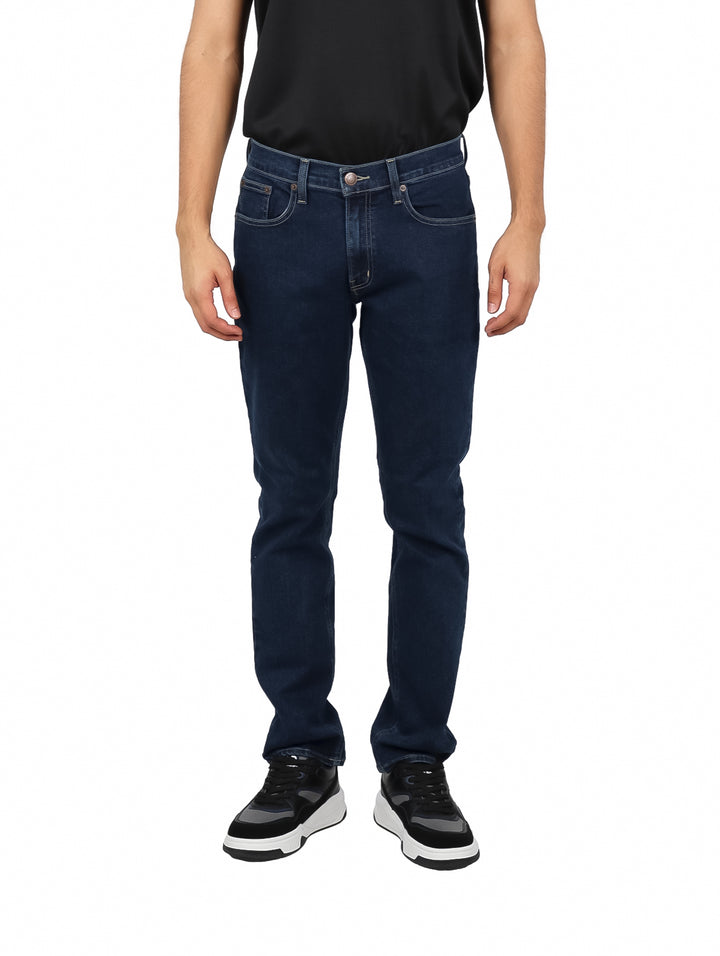 Hombre vistiendo jeans azul oscuro de corte recto sobre fondo blanco.