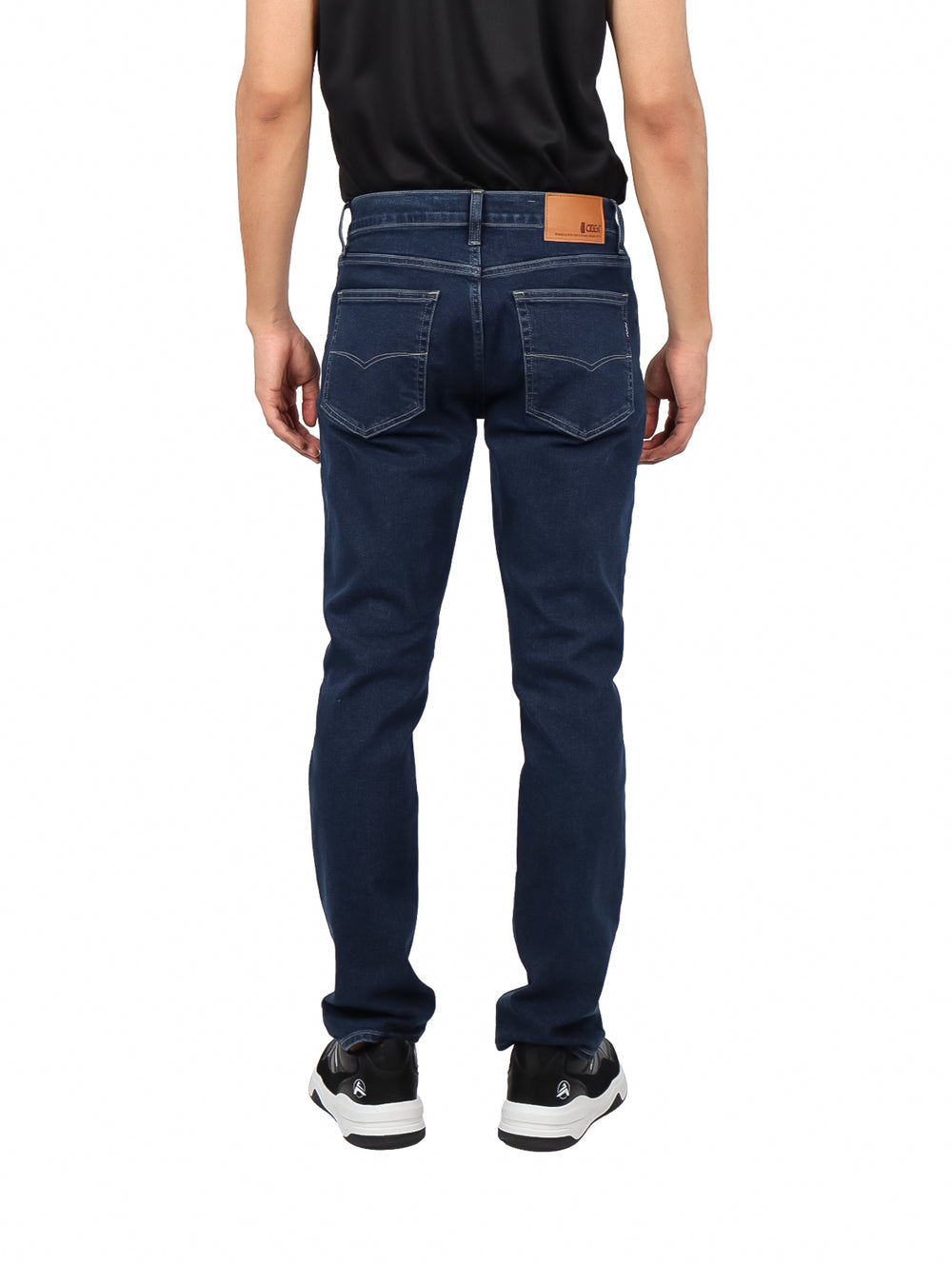 Hombre vistiendo jeans azul oscuro de corte recto sobre fondo blanco.