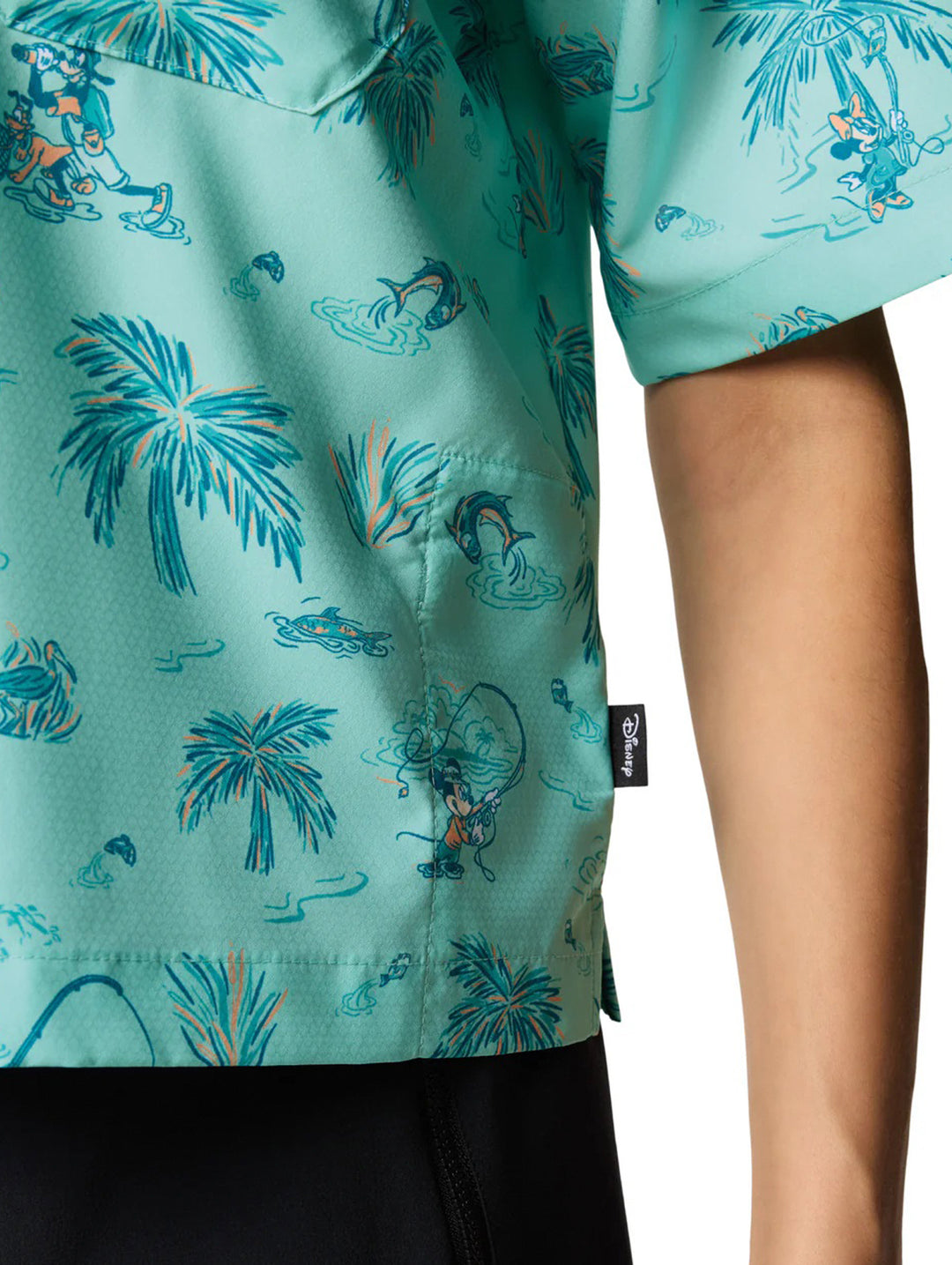 Mujer vistiendo camisa Columbia color verde menta con estampado tropical de palmeras y shorts negros.