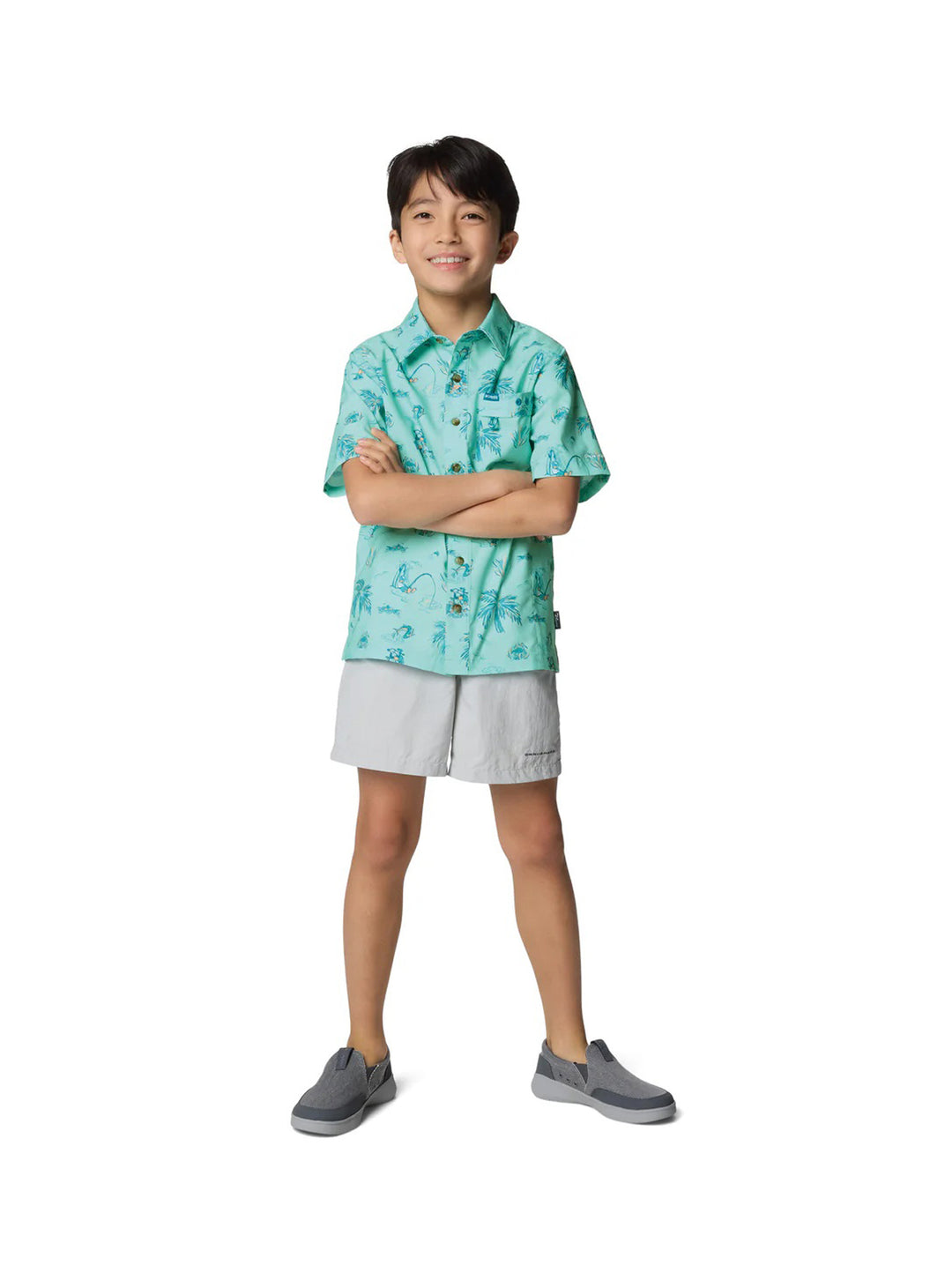 Niño vistiendo una camisa Columbia de manga corta color turquesa con estampado tropical de palmeras.