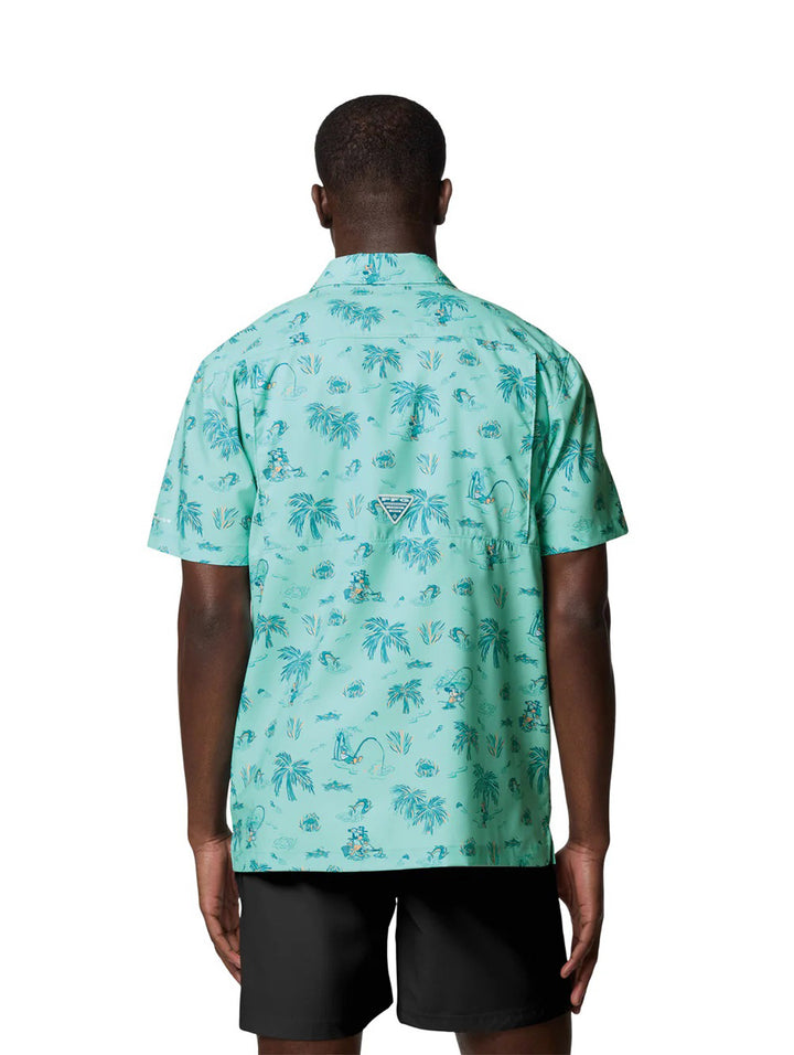 Hombre vistiendo camisa Columbia de manga corta color turquesa con estampado tropical de palmeras.