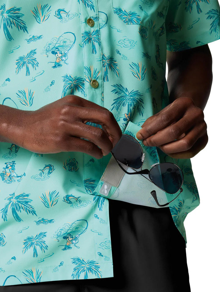 Hombre vistiendo camisa Columbia de manga corta color turquesa con estampado tropical de palmeras.