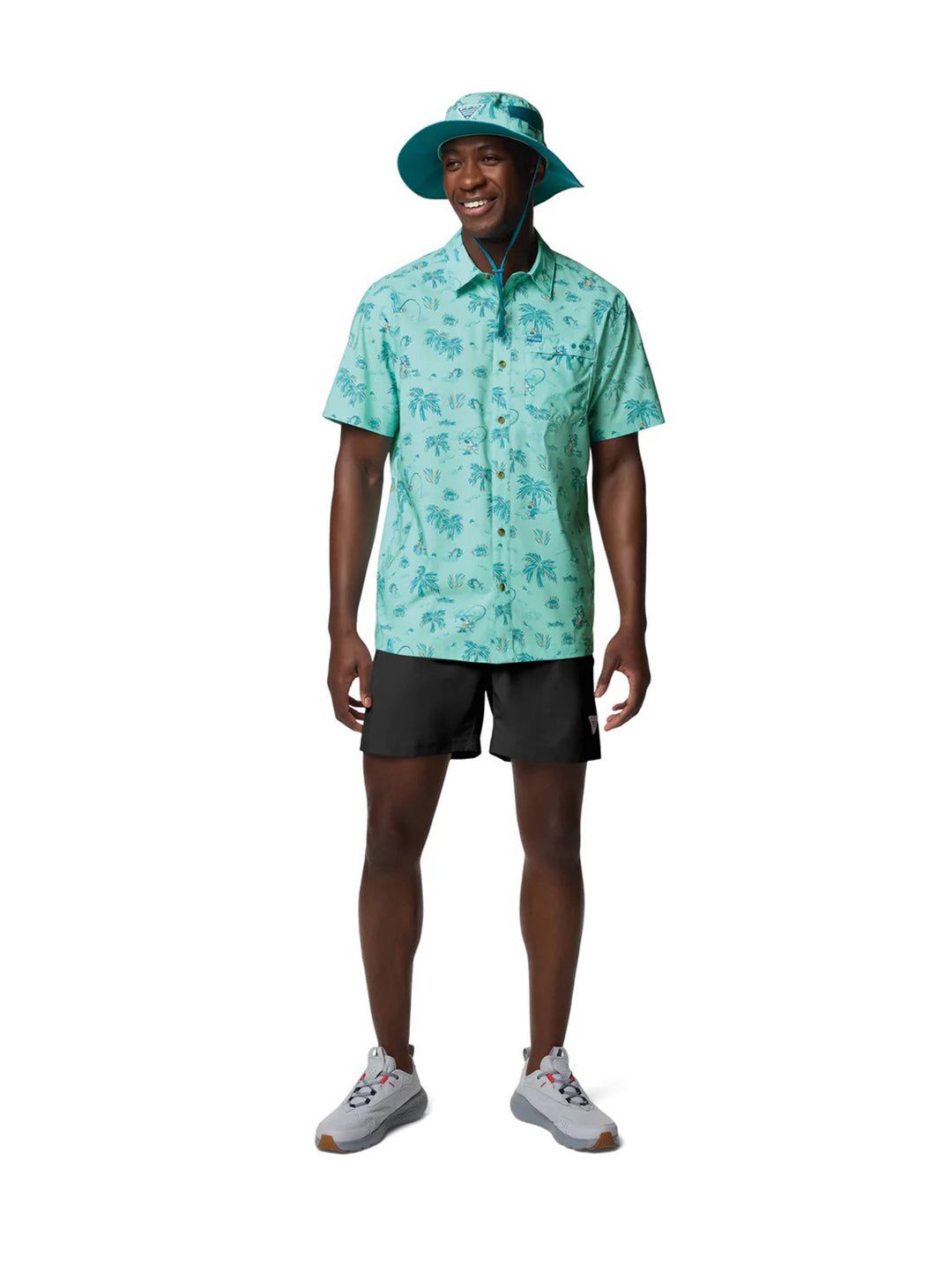 Hombre vistiendo camisa Columbia de manga corta color turquesa con estampado tropical de palmeras.