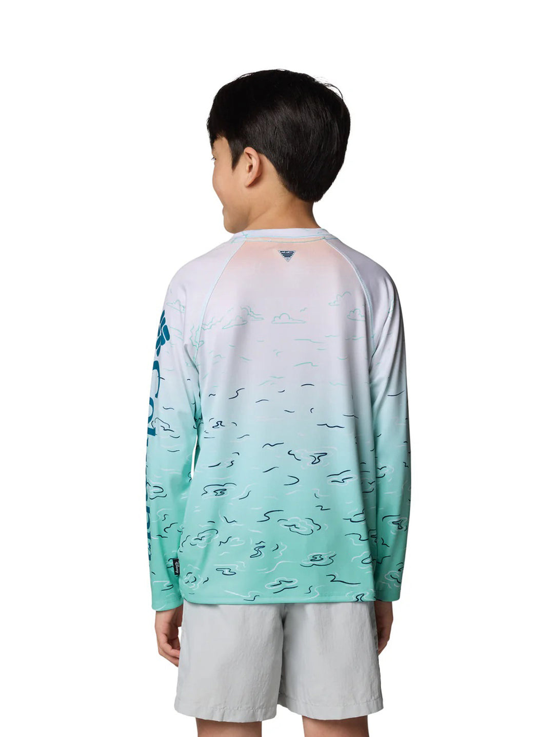 Niño vistiendo playera Columbia de manga larga con degradado de blanco a turquesa y estampado de pesca.