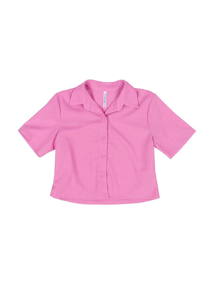 Niña vistiendo una camisa rosa de manga corta con botones y cuello.