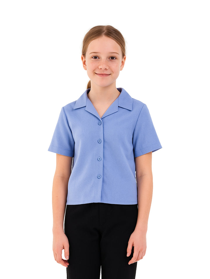 Niña vistiendo una camisa escolar de color azul claro con botones y cuello.