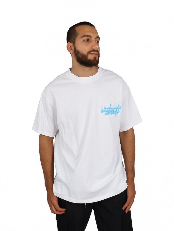 Hombre vistiendo una playera blanca oversize de manga corta con un logo en el pecho.