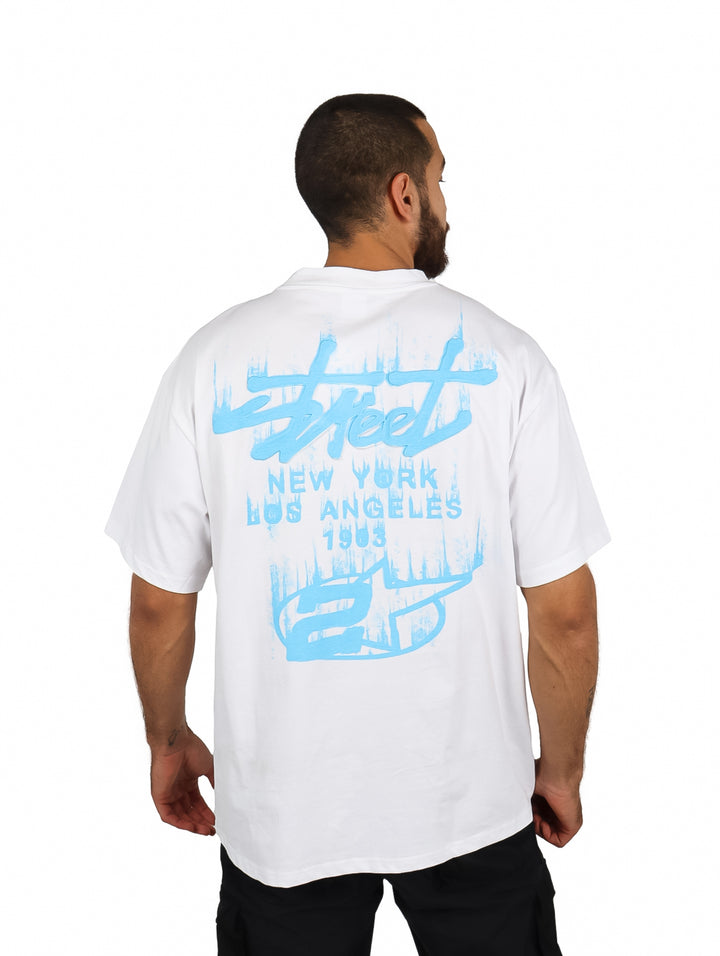 Hombre vistiendo una playera blanca oversize de manga corta con un logo en el pecho.