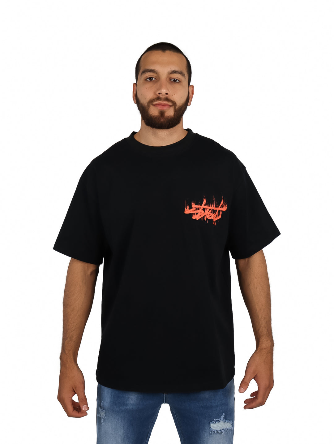 Hombre vistiendo playera oversize color negro con logo rojo en el pecho.