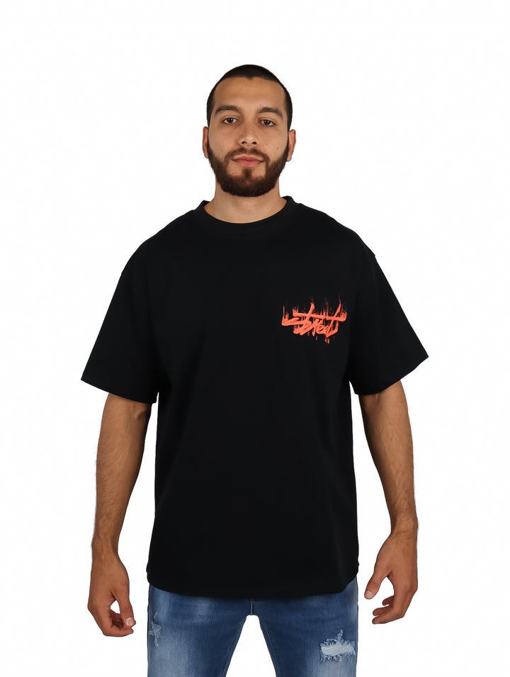 Hombre vistiendo playera oversize color negro con logo rojo en el pecho.
