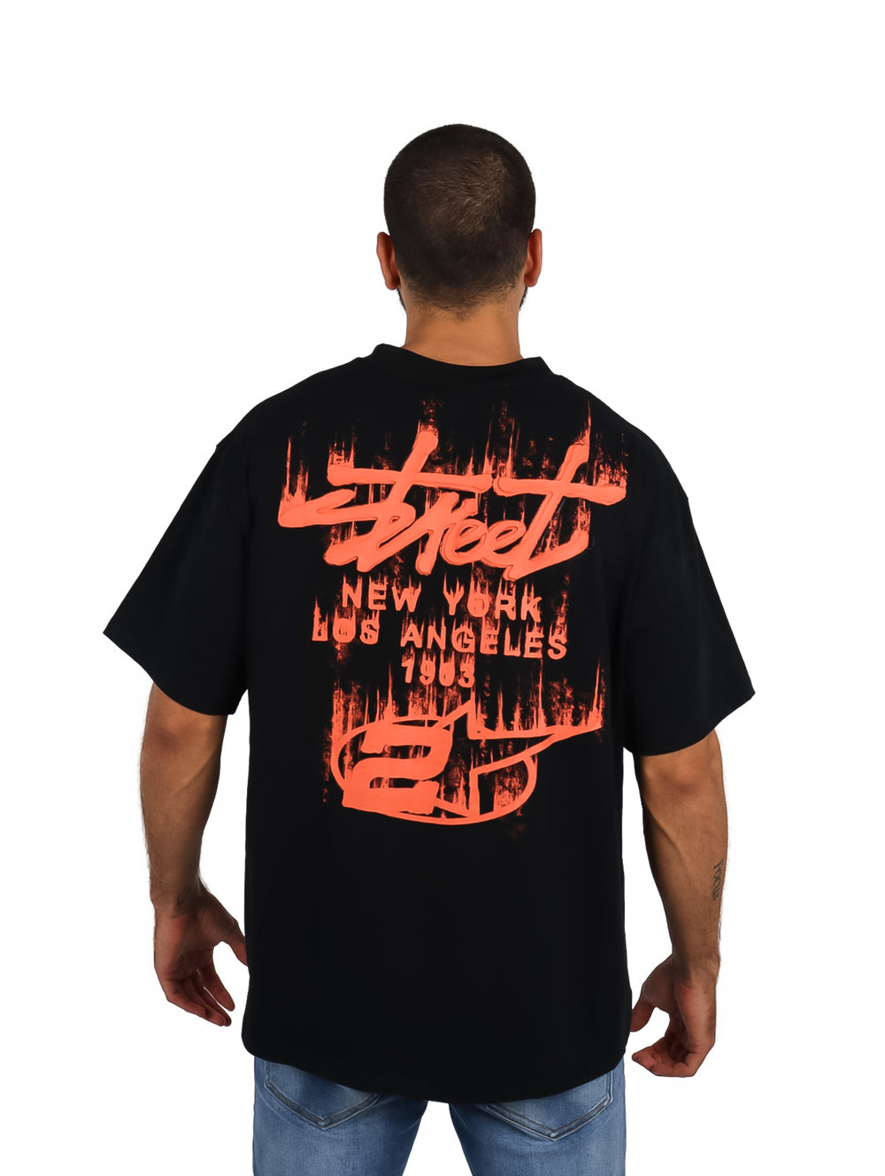 Hombre vistiendo playera oversize color negro con logo rojo en el pecho.