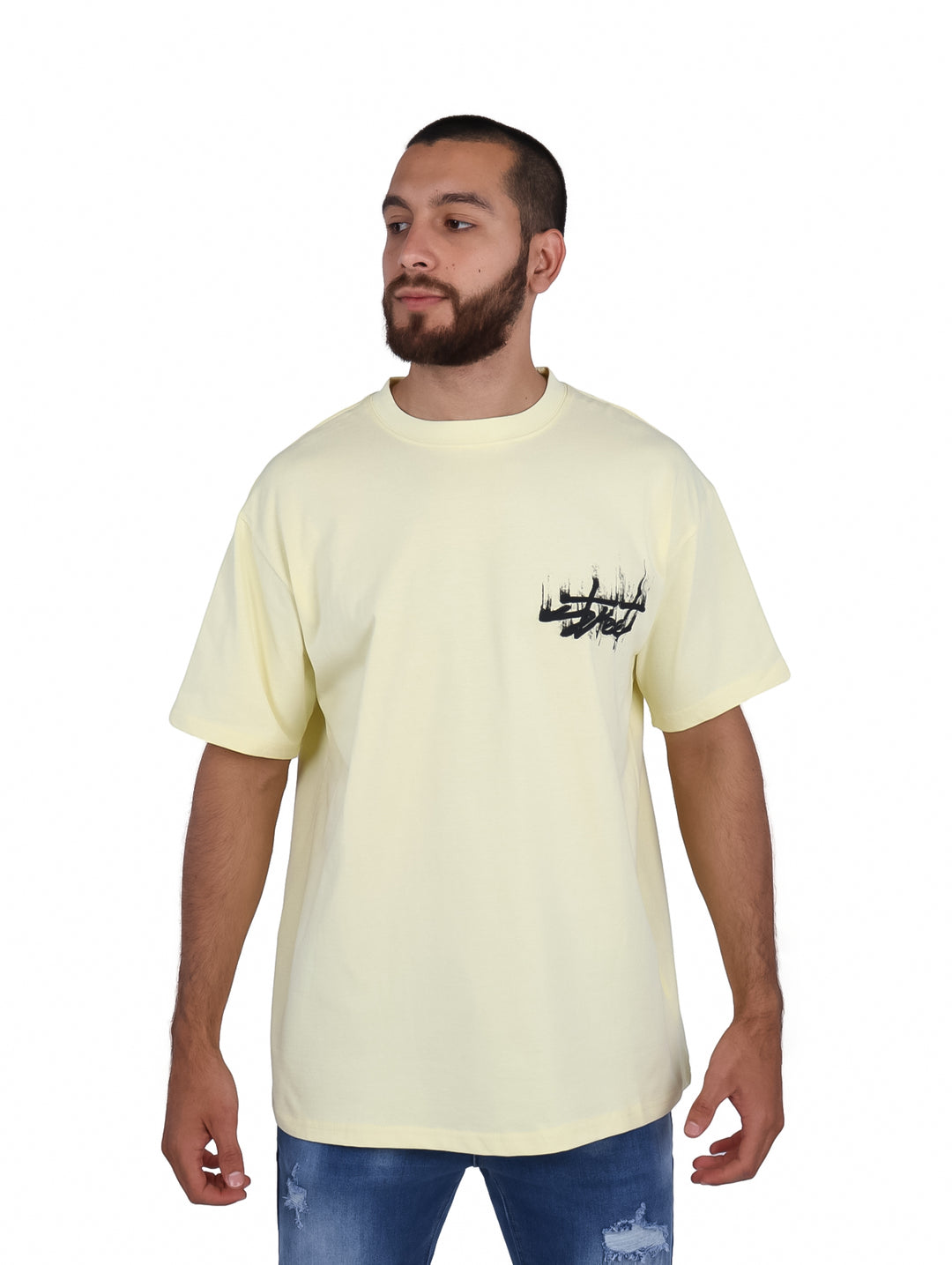 Hombre vistiendo playera oversize color amarillo pálido con un logo negro en el pecho.