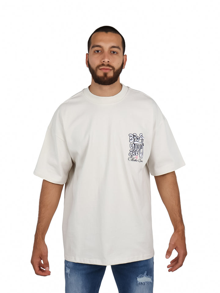 Hombre vistiendo playera oversize color arena con logo en el pecho.