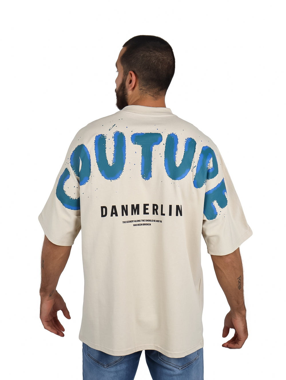 Hombre vistiendo playera beige de manga corta con diseño gráfico azul en el pecho.