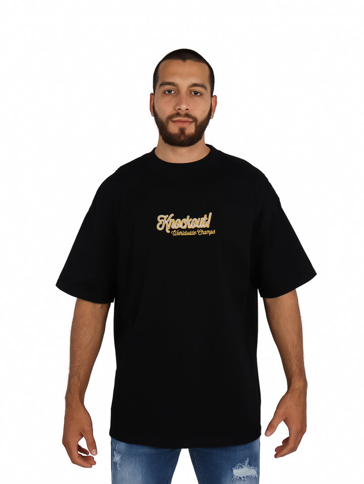 Hombre vistiendo playera negra de manga corta con estampado dorado en el pecho.