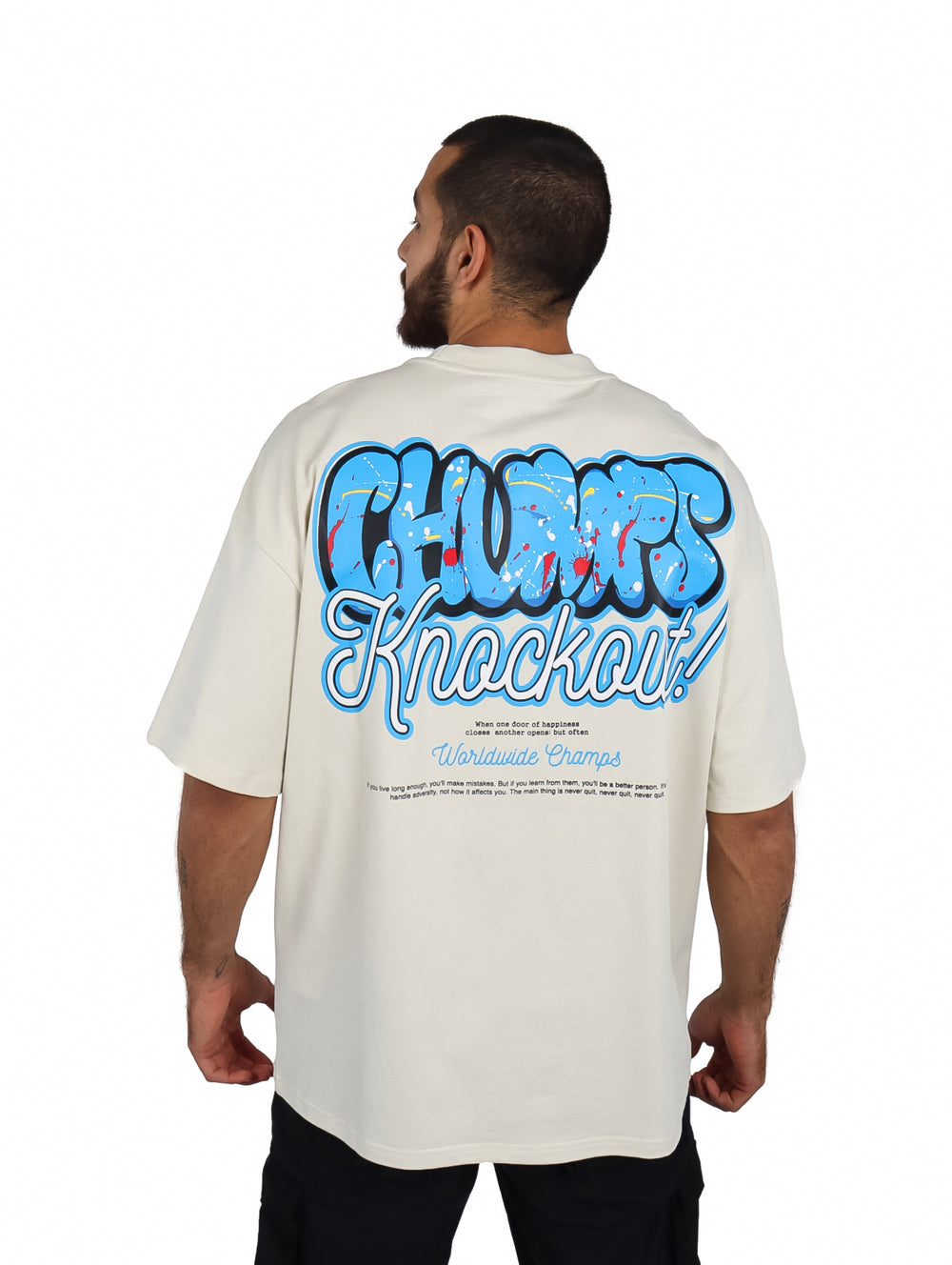 Hombre vistiendo playera oversize color beige con logotipo azul en el pecho.