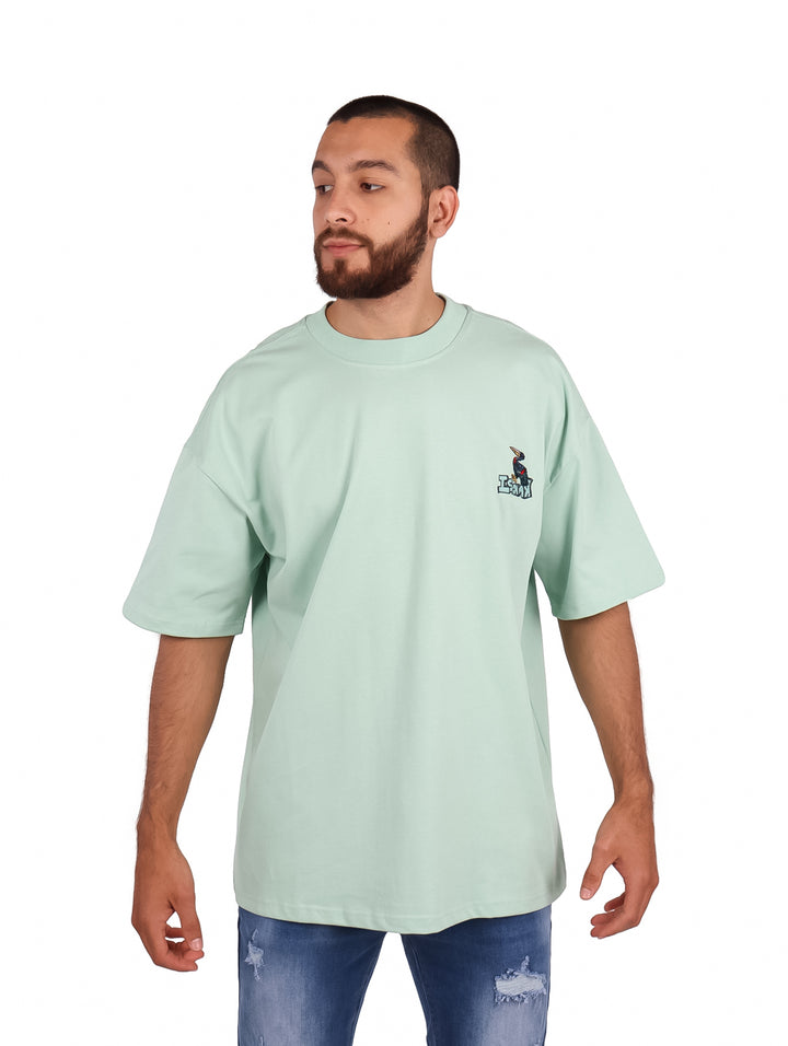 Hombre vistiendo playera oversize color menta de manga corta con un pequeño logo en el pecho.