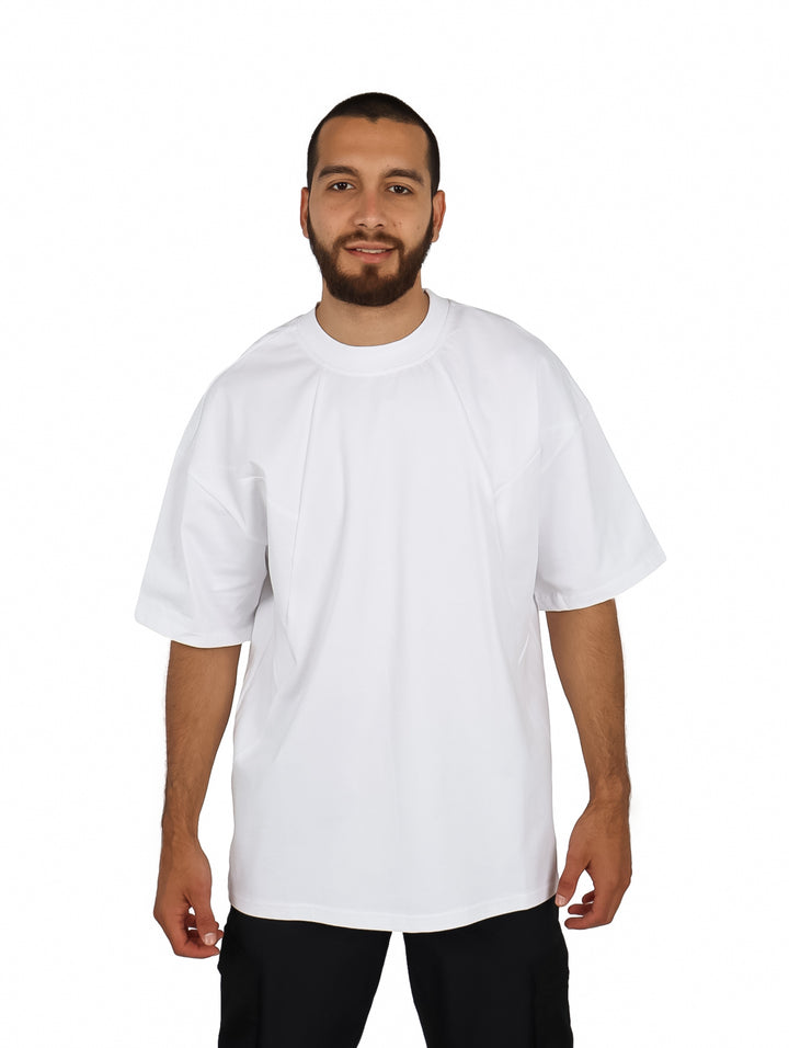 Hombre vistiendo una playera oversize de color blanco con cuello redondo y manga corta.