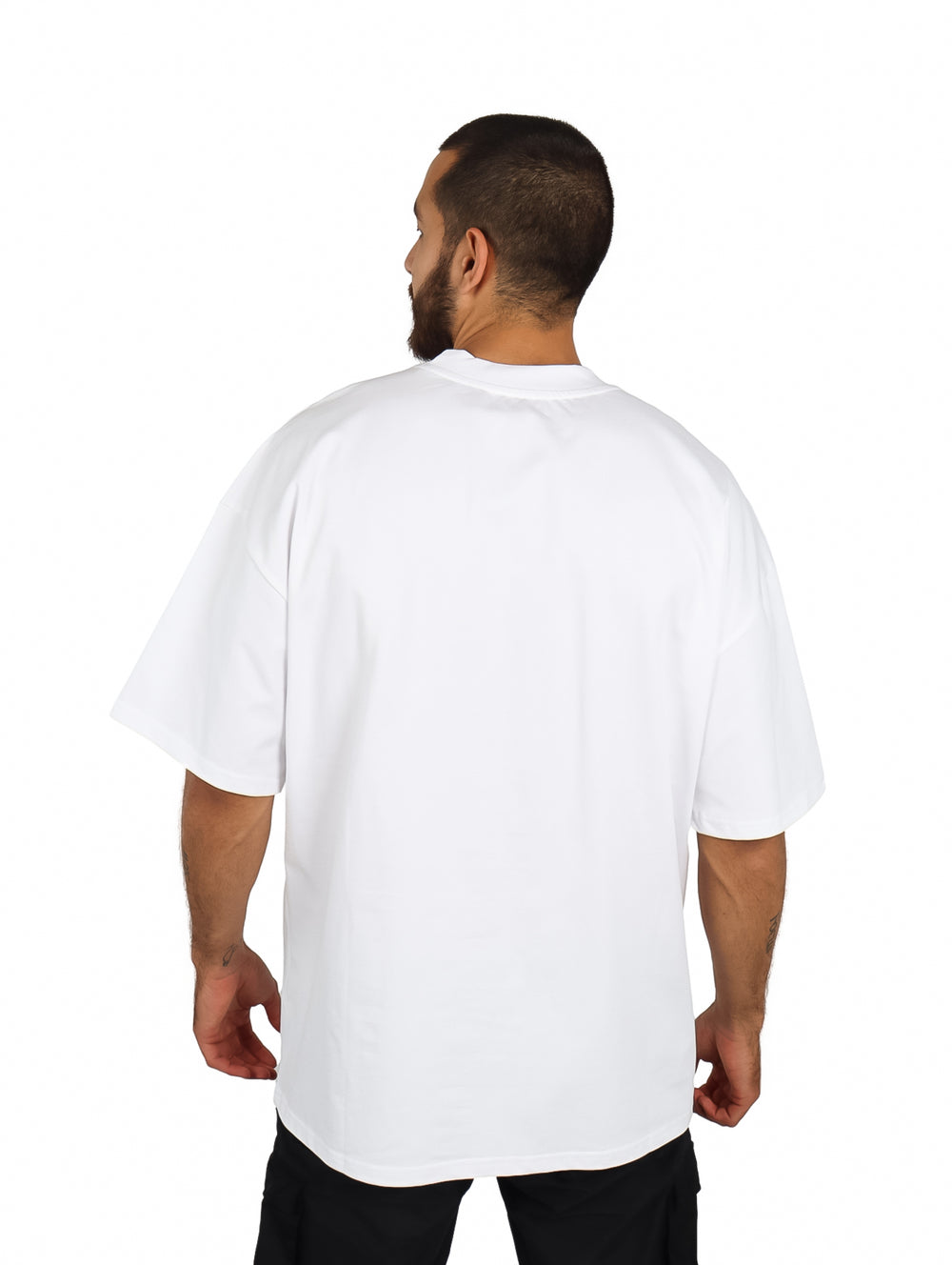 Hombre vistiendo una playera oversize de color blanco con cuello redondo y manga corta.