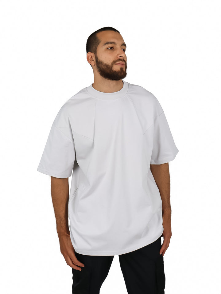 Hombre vistiendo playera oversize de color gris con cuello redondo y manga corta.