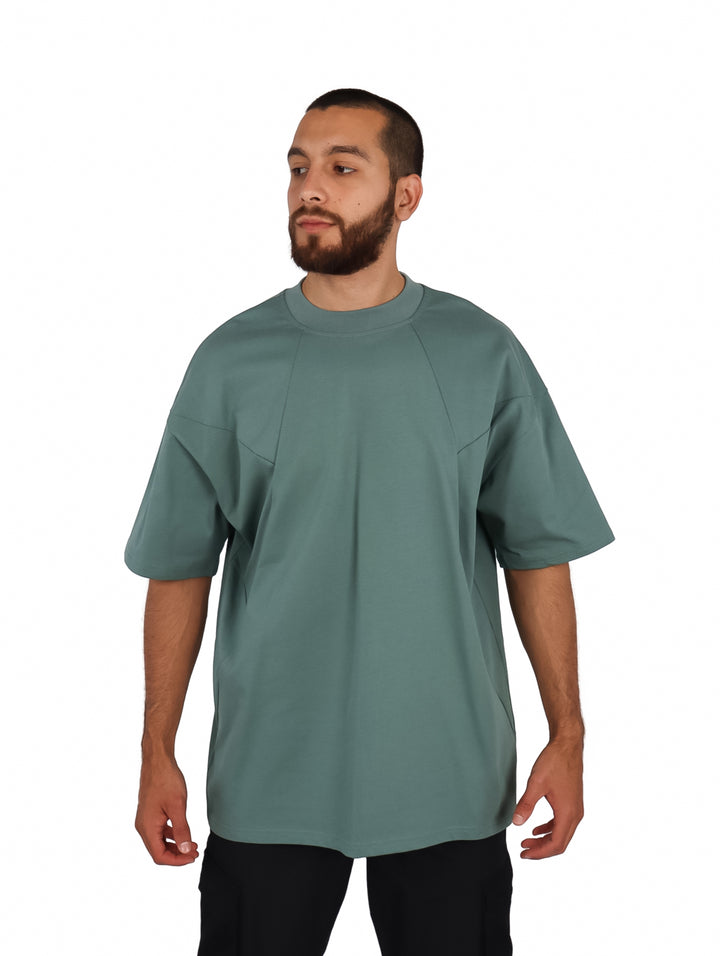 Hombre vistiendo una playera oversize de color verde con cuello redondo y manga corta.