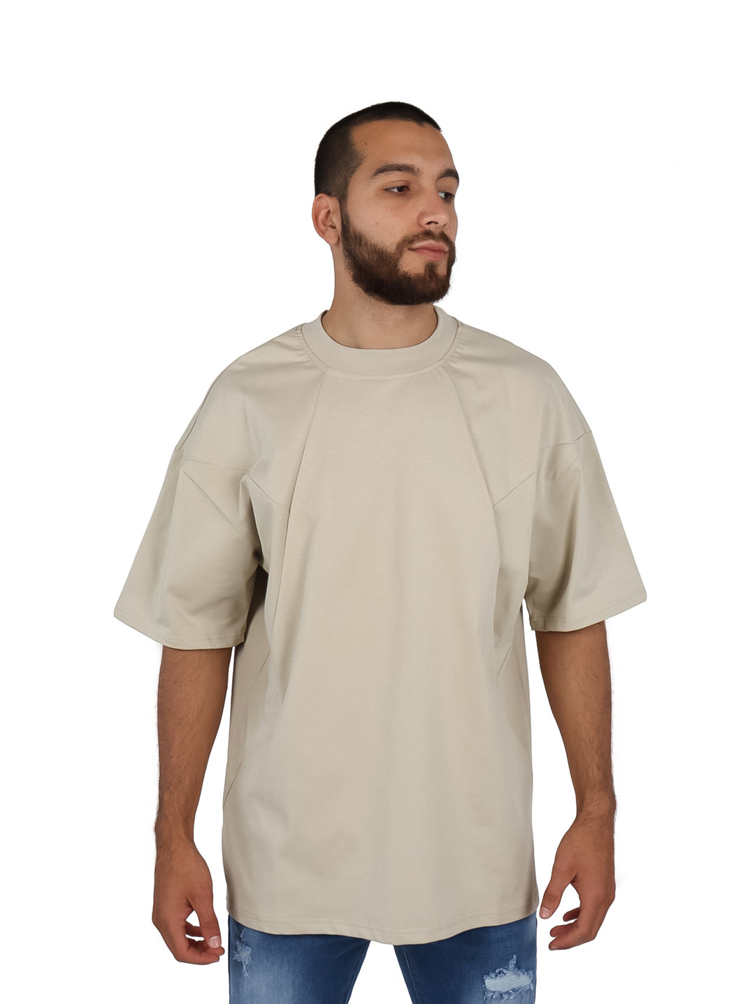 Hombre vistiendo una playera oversize de color khaki con cuello redondo y manga corta.