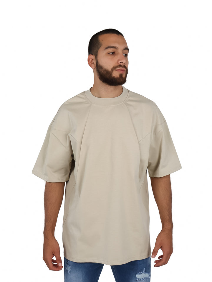 Hombre vistiendo una playera oversize de color khaki con cuello redondo y manga corta.